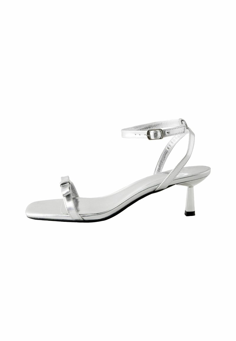 Silver metallic high-heeled sandal with an open toe, slender ankle strap, and a kitten heel. Features a minimalist design and smooth texture.