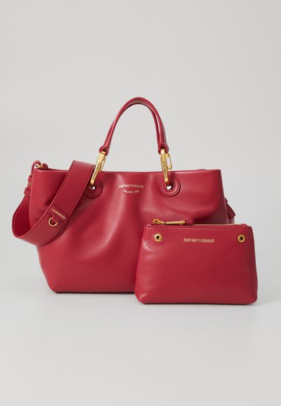 Red leather handbag set with a large tote featuring gold hardware and a smaller matching clutch. Smooth texture with embossed logo detail.