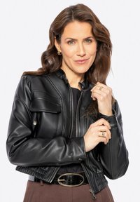 Giacca in pelle nera corta con chiusura a zip e bottone, dotata di un design aderente, tasche laterali e dettagli a coste all'orlo.