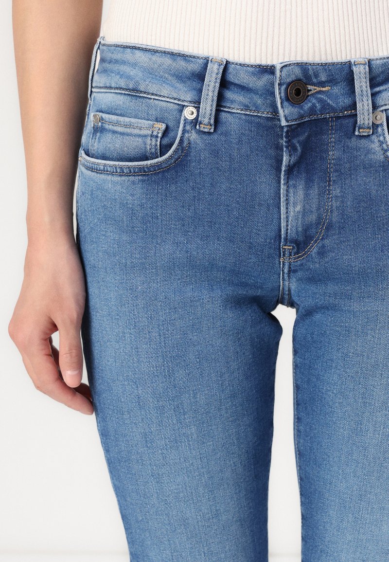 Hellblaue Denim-Jeans mit schmaler Passform, Fünf-Taschen-Stil und subtilen Auswaschungen im Stoff. Metallknopfverschluss.