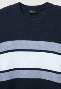 Dunkelblaues Sweatshirt mit horizontalen Streifen in Hellgrau, Dunkelgrau und Weiß. Gerippter Rundhalsausschnitt und weiche, gestrickte Textur. Markenlabel sichtbar.
