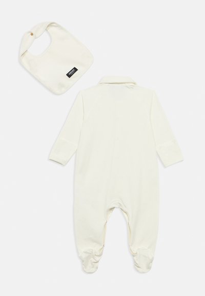 Ελέφαντας ολόσωμη φόρμα με μακριά μανίκια, γιακά και κουμπώματα με σούστες, συνοδευόμενη από ένα ταιριαστό σαλιαράκι με ετικέτα λογότυπου. Μαλακή, λεία υφή υφάσματος.