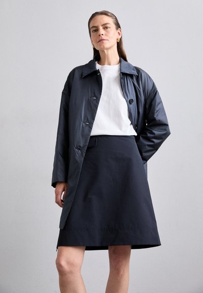 Marineblaue gepolsterte Jacke mit klassischem Kragen, vorderem Knopfverschluss und langen Ärmeln, kombiniert mit einem passenden marineblauen knielangen Rock.