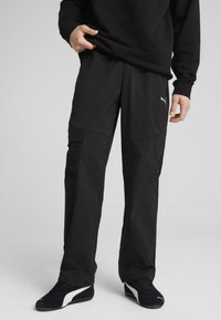 Melni sporta bikses ar brīvu piegriezumu, ar kabatu ar rāvējslēdzēju, vieglu audumu un diskrētu logotipa akcentu sānos.