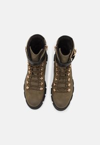 Stivali da trekking color khaki con rifiniture in pelle nera, ganci per lacci in oro rosa e fodera in tessuto testurizzato. Presentano una suola resistente per una migliore aderenza.