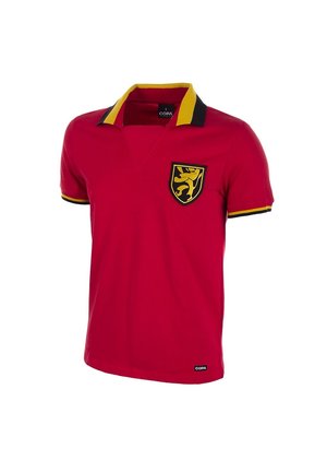 Red short-sleeve polo shirt with black and yellow collar and sleeve trim, featuring a yellow lion crest on the left chest and a COPA logo near the hem.