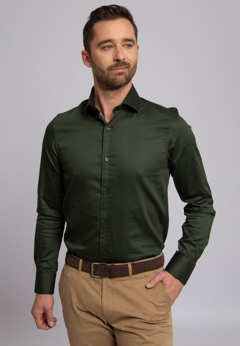 Groen satijnen overhemd met een puntige kraag en lange mouwen, voorzien van een knoopsluiting aan de voorkant en een gladde textuur, gecombineerd met khakibroek.