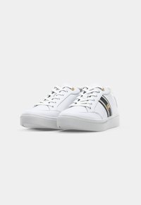 Sneakers bianchi con una texture in pelle liscia, caratterizzati da una striscia di accentuazione nera e oro, punta rotonda e suola piatta.