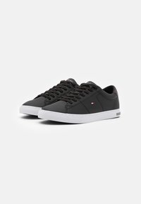 Sneakers in pelle nera con suola in gomma bianca, punta rotonda e chiusura con lacci. Logo del marchio ben visibile sul lato.