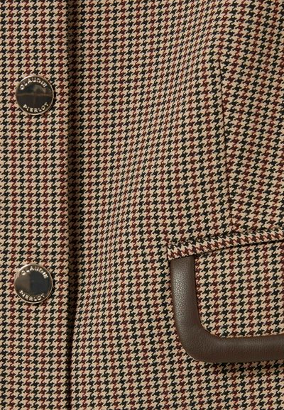 Tissu à motif pied-de-poule marron et beige avec des boutons métalliques et un détail de poche bordée de cuir. La texture semble tissée.