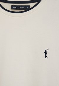 Polo bianca con bordo del colletto blu navy e silhouette ricamata blu navy di una persona che tiene una mazza da polo sul petto.