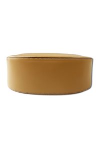 Ottoman rond en cuir lisse couleur fauve avec des coutures visibles. Forme simple, dessus rembourré et texture uniforme sans motifs ni accents.