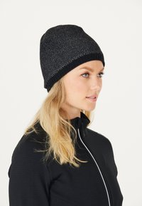 Sort strikket hue med et struktureret mønster, der har en kontrasterende sort ribbet manchet. Blødt materiale for komfort og varme.