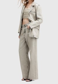 Vaaleanharmaa farkkutakki, jossa on rento leikkaus, yhdistettynä samaan sävyyn olevaan lyhytvartiseen puseroon ja leveälahkeisiin housuihin. Mustat kengät viimeistelevät ilmeen.