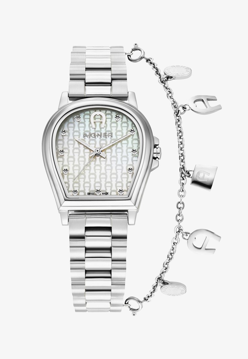 Hopeakylkinen ruostumattomasta teräksestä valmistettu kello, jossa on pisaran muotoinen rakenne, kuvioitu hopeinen kellotaulu ja kristallikohdistimet. Mukana koristeellinen hopeaketju.