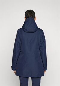 Marine vanntett jakke med hette, enkelt design og elastiske mansjetter. Har en ryggbakkde og lett A-formet silhuett.