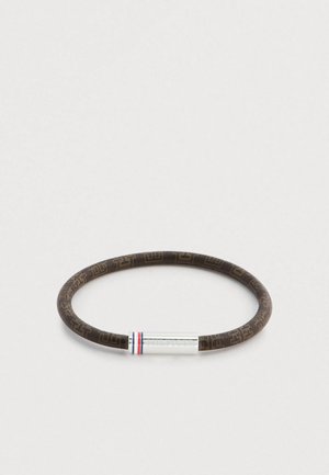 Braunes Armband aus Gummi mit Muster und silbernem Metallakzent, der rote und blaue Streifen zeigt. Runde Form, glatte Textur.