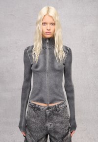 Gestreiftes, tailliertes Zip-Up-Oberteil in Schwarz und Grau, mit langen Ärmeln und einem hohen Kragen. Texturiertes Ripp-Gewebe erhöht das visuelle Interesse.