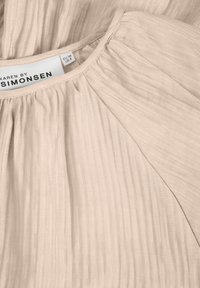 Robe en tissu plissé beige clair avec encolure ronde, affichant l’étiquette de la marque "Karen by Simonsen" et les tailles EU 38, US 8.