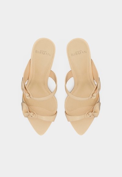 Μπεζ σανδάλια με μυτερή μύτη, χωρίς κορδόνια, με λεπτές λουράκια και μικρές λεπτομέρειες φιόγκου, με το λογότυπο Alexandre Birman στις εσωτερικές σόλες.