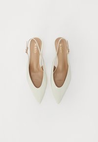 Zapatos slingback de punta en cuero sintético verde claro, con plantilla beige y herrajes en tono dorado para la correa ajustable.