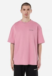 Tricou roz supradimensionat din bumbac, cu mâneci scurte și guler rotund. Text mic cu logo gri pe piept.
