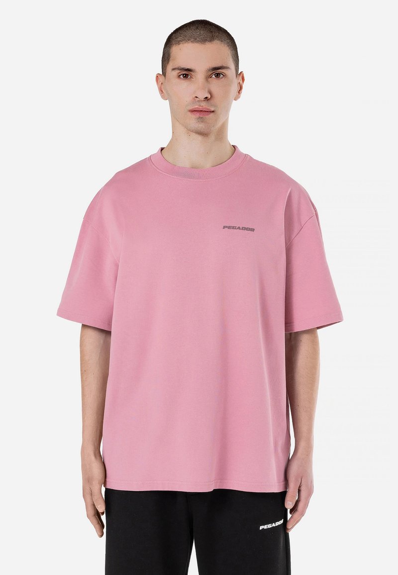Tricou roz supradimensionat din bumbac, cu mâneci scurte și guler rotund. Text mic cu logo gri pe piept.