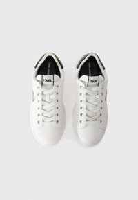 Sneakers bianchi in pelle con punta rotonda, suola piatta bianca, dettagli argentati sul tallone e branding interno nero. Presentano lacci standard.