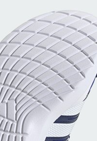 White rubber sole with a textured, diamond-pattern tread. Features navy accents on a white upper with a honeycomb texture.