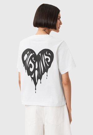 Vit bomulls t-shirt med en stor svart droppande hjärta-design på baksidan. Korta ärmar och en avslappnad passform.