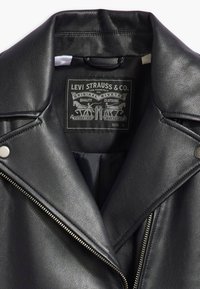 Czarna skórzana kurtka z metalowym suwakiem, zatrzaskami i metką "Levi Strauss & Co.", charakteryzująca się teksturowanym wykończeniem i wyraźnym kołnierzem.