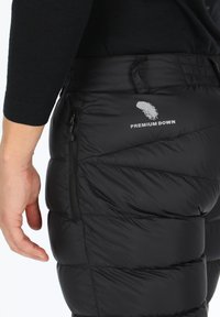 Zwarte opblaasbare geïsoleerde broek met een zijzak met rits, gestikt patroon en een "Premium Down" logo met een veerafbeelding op de achterkant.