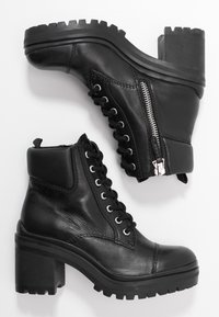 Bottines en cuir noir avec un talon épais, design à lacets, fermeture éclair sur le côté et semelle robuste pour une meilleure adhérence. Fini texturé.