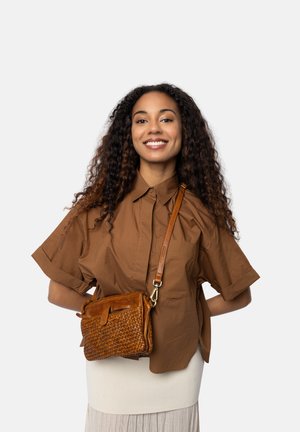Borsa a tracolla in pelle intrecciata marrone con forma piatta, superficie testurizzata e tracolla regolabile, appoggiata su un vestito chiaro.