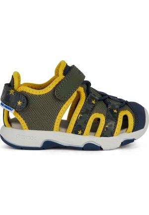 Sandalia verde y amarilla con tejido de malla, suela de goma, correa de gancho y bucle, y detalle de patrón de camuflaje; diseñada para la transpirabilidad y la comodidad.