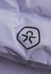 Ljus lavendelfärgad tyg med en slät struktur, som har en svart logotyp inom en sköld. Designen betonar en stilren, modern estetik.