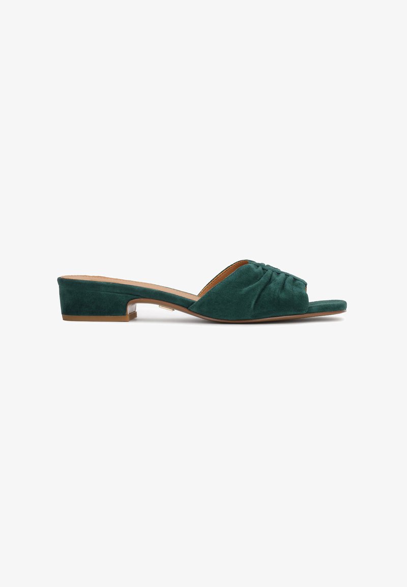 Mules en daim vert avec un petit talon carré, présentant un design avant drapé et une doublure intérieure lisse, offrant une silhouette simple et élégante.