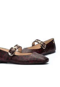Bailarinas de cuero burdeos con punta afilada, que presentan una hebilla dorada decorativa en una correa. Patrón de print de leopardo texturizado. Taco bajo.