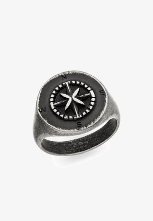 Antikmetallring med hævet kompasrose og grundretninger indgraveret på rund skive, børstet metalbånd synligt indvendigt.