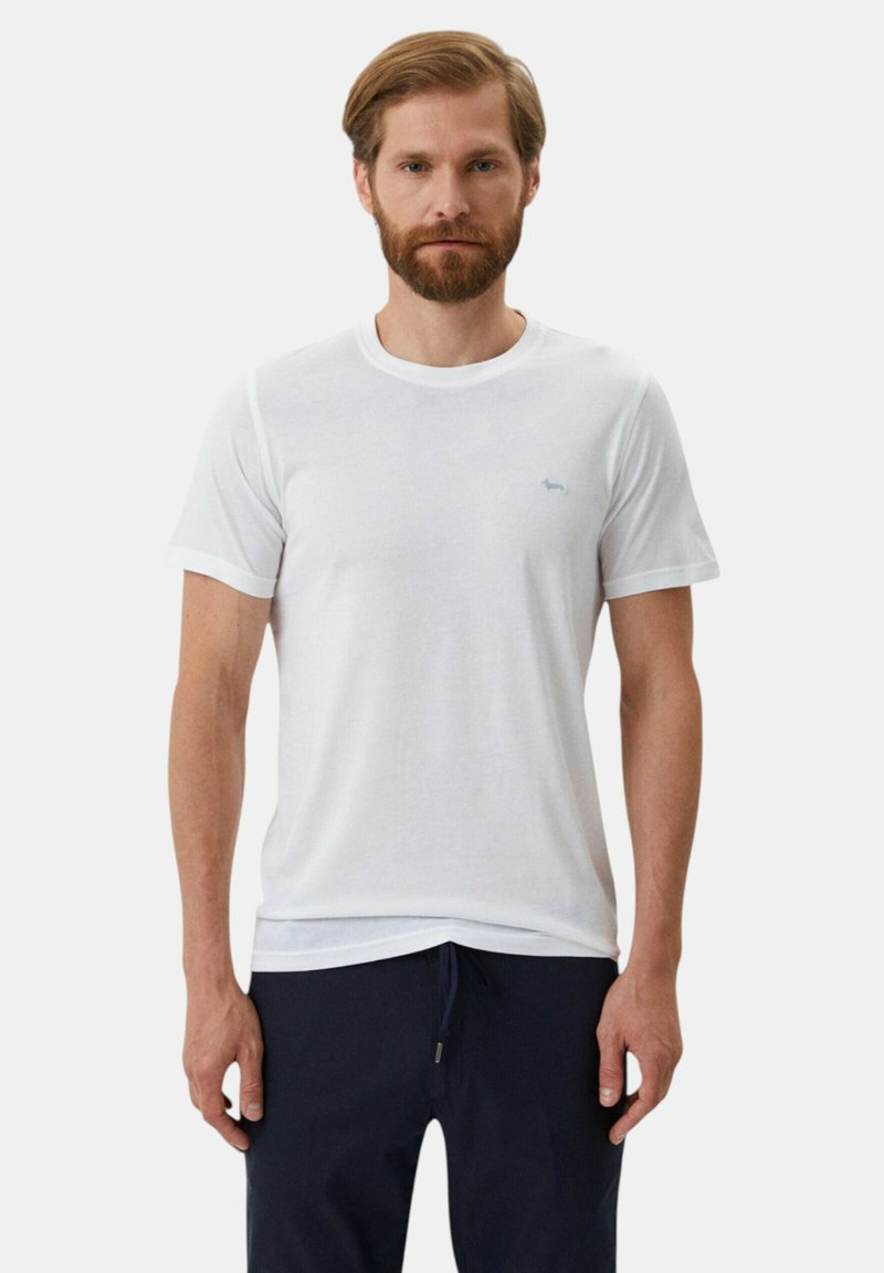 T-shirt bianco in cotone con maniche corte, scollo rotondo e un logo azzurro chiaro discreto sul petto. La vestibilità è casual e rilassata.