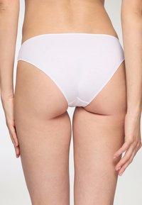 Mutande bikini in cotone bianco con taglio a vita bassa, caratterizzate da una texture liscia e senza cuciture visibili né fantasie.