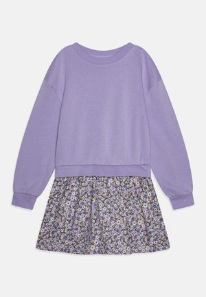 Lilla genserlignende topp med lange ermer og en samlet skjørt i blomstermønster med hvite, gule og lilla blomster.