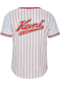 Tricou alb cu dungi verticale roșii. Are logo-ul "Kani" și "est. 1989" în roșu pe spate. Mâneci scurte și tiv rotunjit.