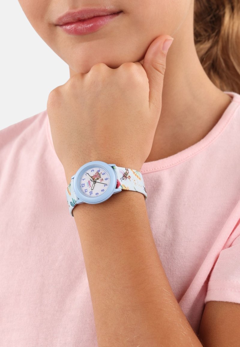 Blauwe horloge met een stofband met bloemenpatroon, voorzien van een ronde witte wijzerplaat en paarse uurmarkers, gedragen om een pols. Roze shirt op de achtergrond.