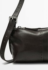 Borsa a spalla in pelle nera con finitura texturizzata, chiusura superiore con zip e tracolla regolabile con fibbia in argento e dettagli di cucitura visibili.