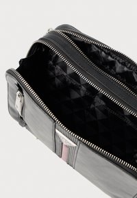 Μαύρη δερμάτινη τσάντα με ασημί μεταλλικά στοιχεία, κλείσιμο με φερμουάρ και εσωτερική επένδυση με διαμάντι μοτίβο. Διαθέτει ροζ τόνους και πολλαπλές θήκες.