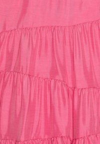 Rosa Kleidungsstoff mit gestuften Rüschchen, glatter Textur und subtiler Ausstrahlung. Reihen von gerafftem Stoff erzeugen ein geschichtetes Erscheinungsbild.