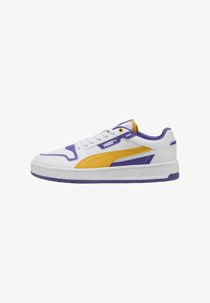 White sneaker featuring purple and yellow accents, smooth leather material, rounded toe, padded collar, and textured rubber sole with grooves.