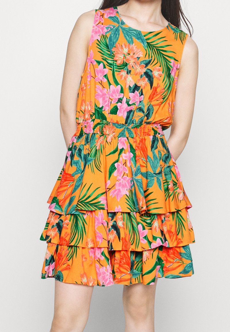 Robe sans manches avec base orange, jupe en couches et imprimé floral coloré avec des fleurs roses, orange et des feuilles vertes.