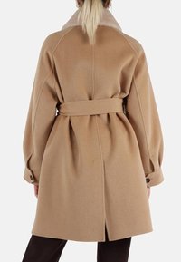 Cappotto in misto lana beige con vita regolabile, colletto oversize e polsini abbottonati. Tessuto morbido con una vestibilità rilassata e dettagli cuciti.